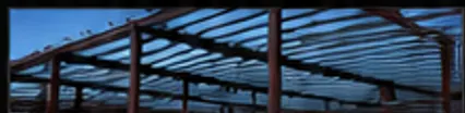 Large steel-framed building under construction with decking installed