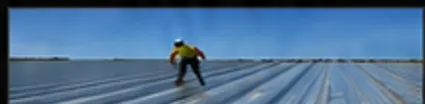 Worker walking across a large metal roof decking installation